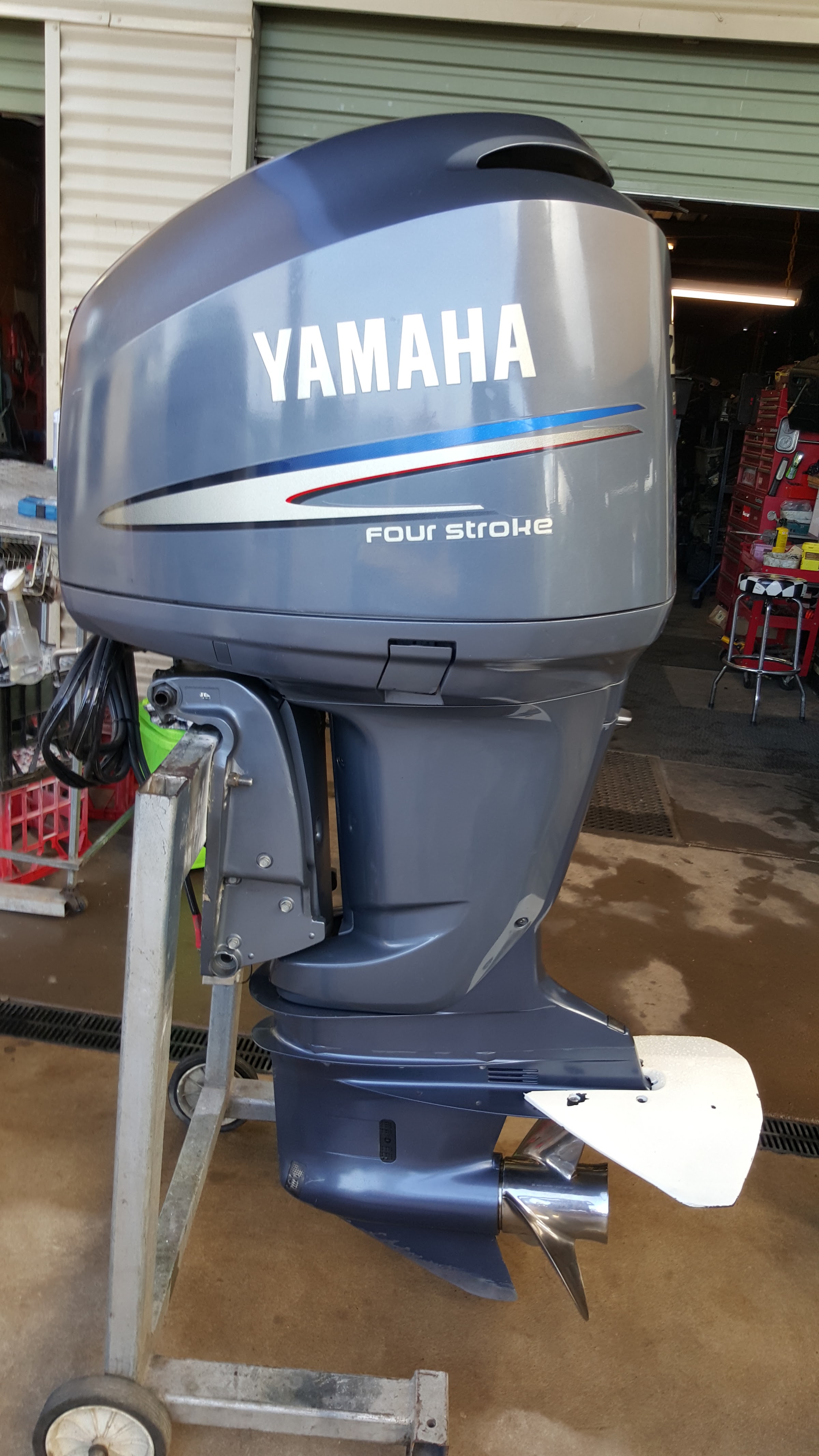 A Yamaha four stroke outboard on a trolley in the workshop doorway