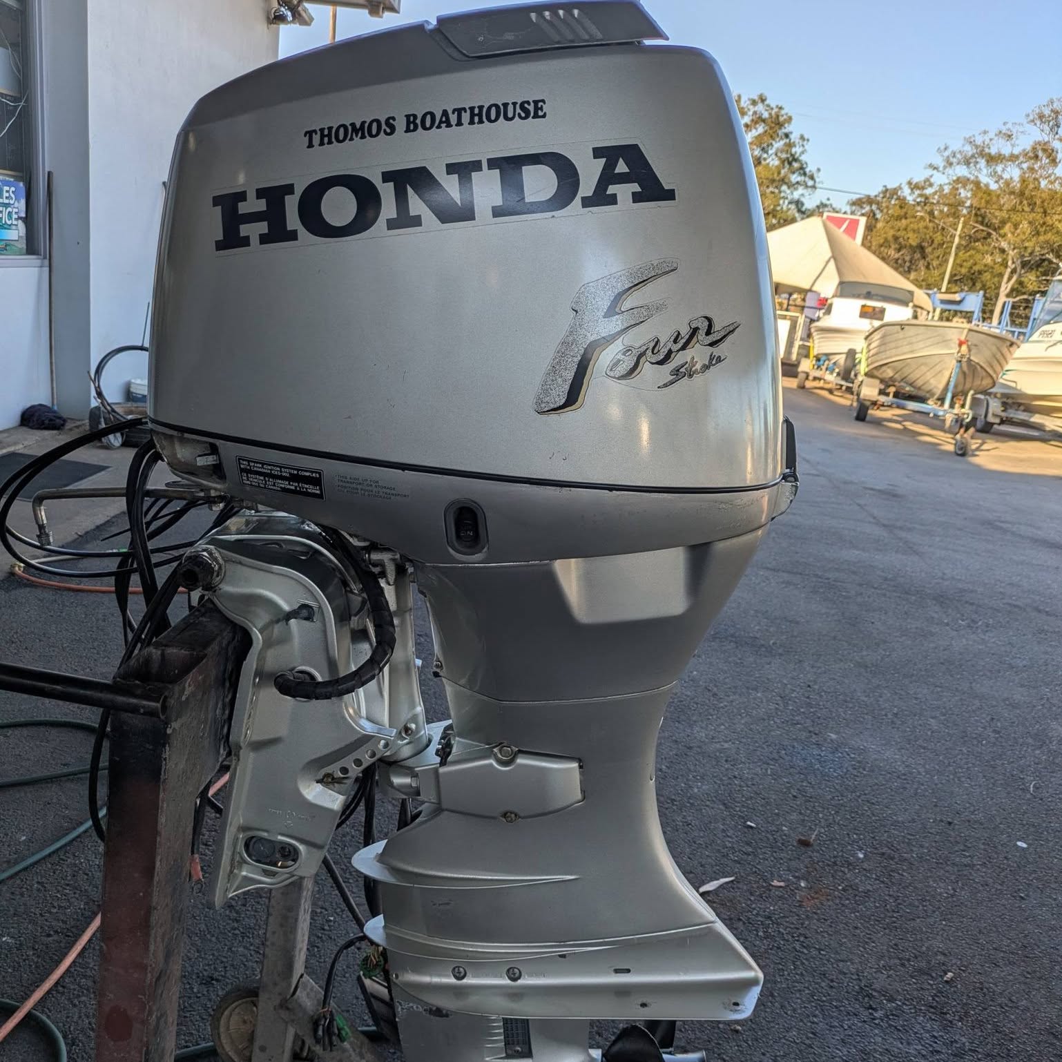 A Honda four stroke outboard with boats on trailers behind it