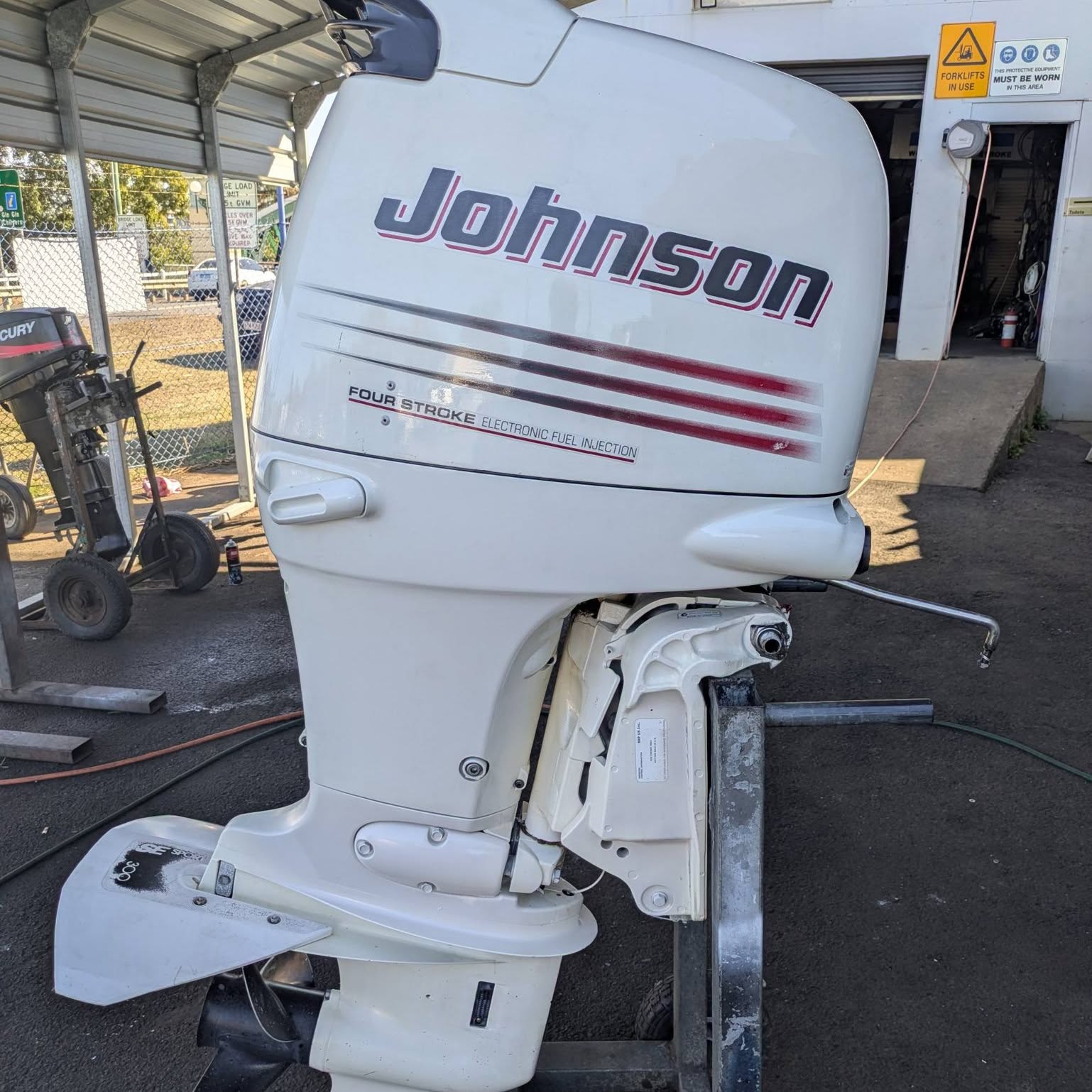 A Johnson four stroke with electronic fuel injection outside the workshop roller door