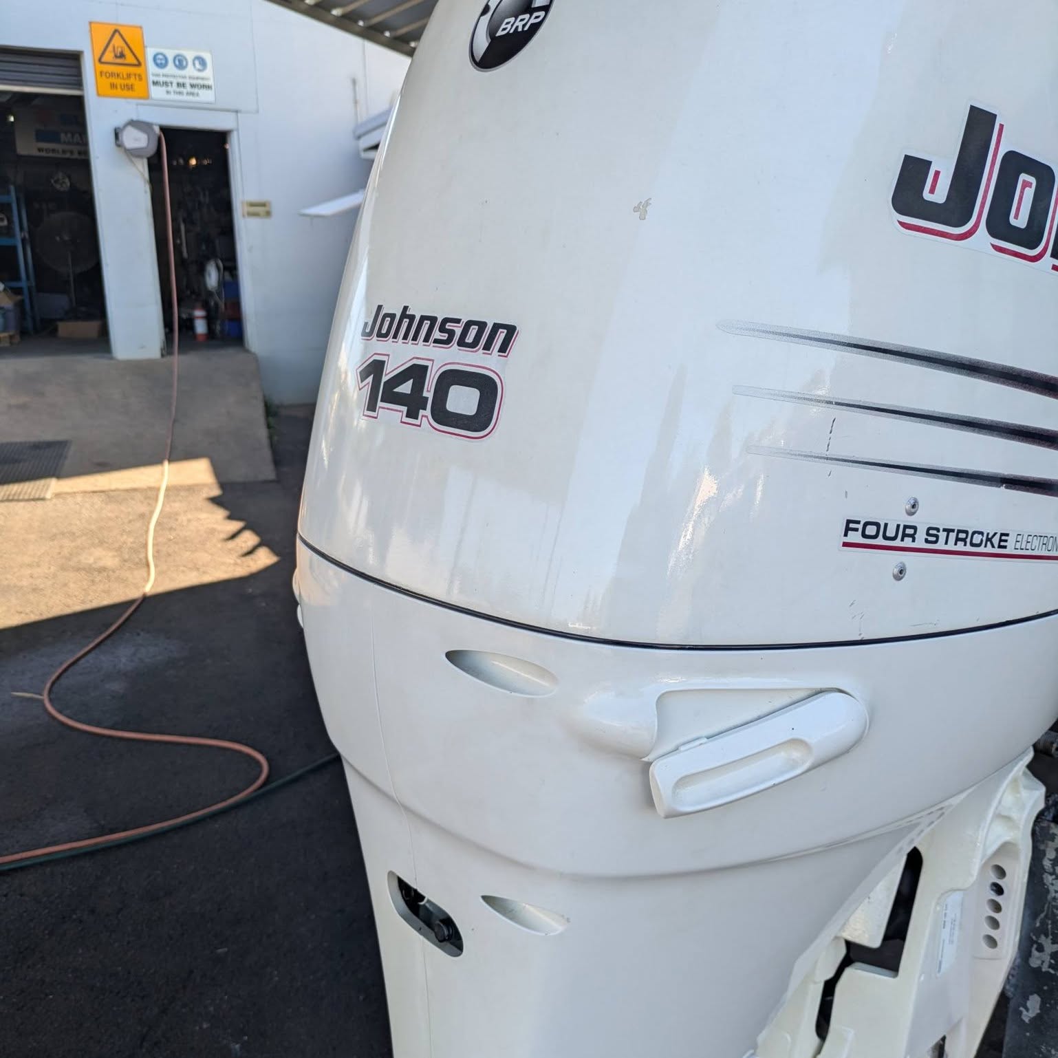 A Johnson 140 four stroke outboard on a stand by the workshop