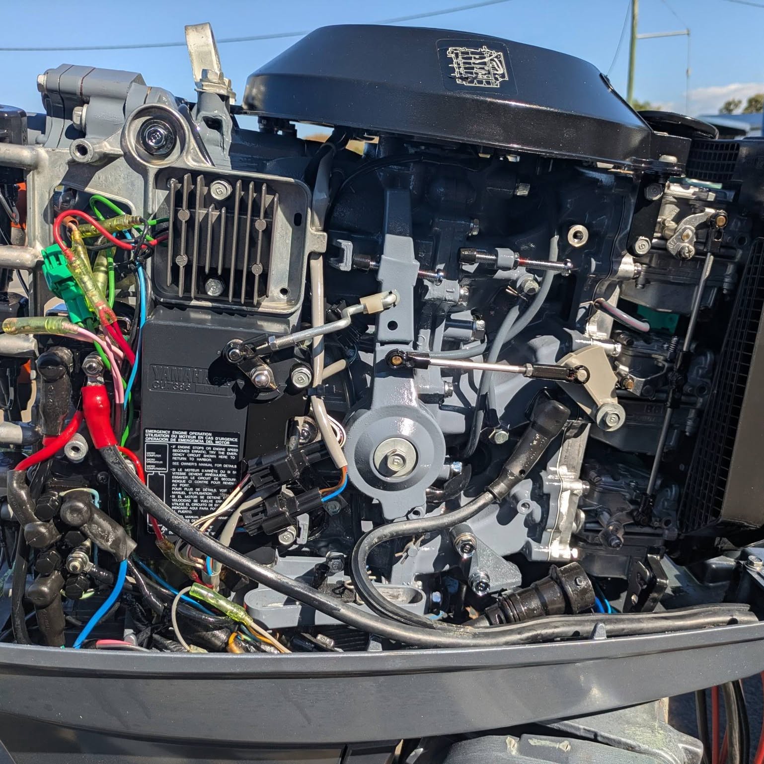 A Yamaha powerhead with the cowl off, looms and linkages exposed on the bench